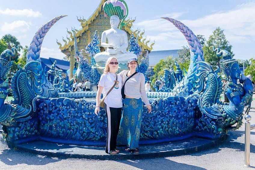 A large blue dragon sculpture with a seated figure in the background. 1
