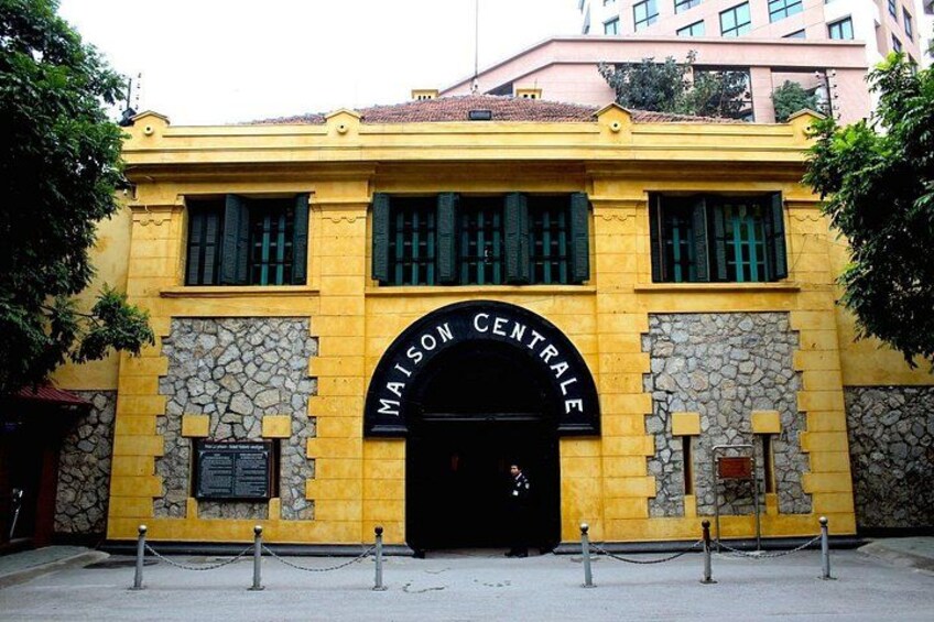 Un edificio amarillo con fachada de piedra y una entrada arqueada negra con el letrero 'MAISON CENTRALE'. 3