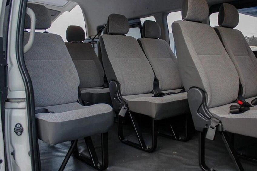 A vehicle interior with four grey seats and a central aisle. 2