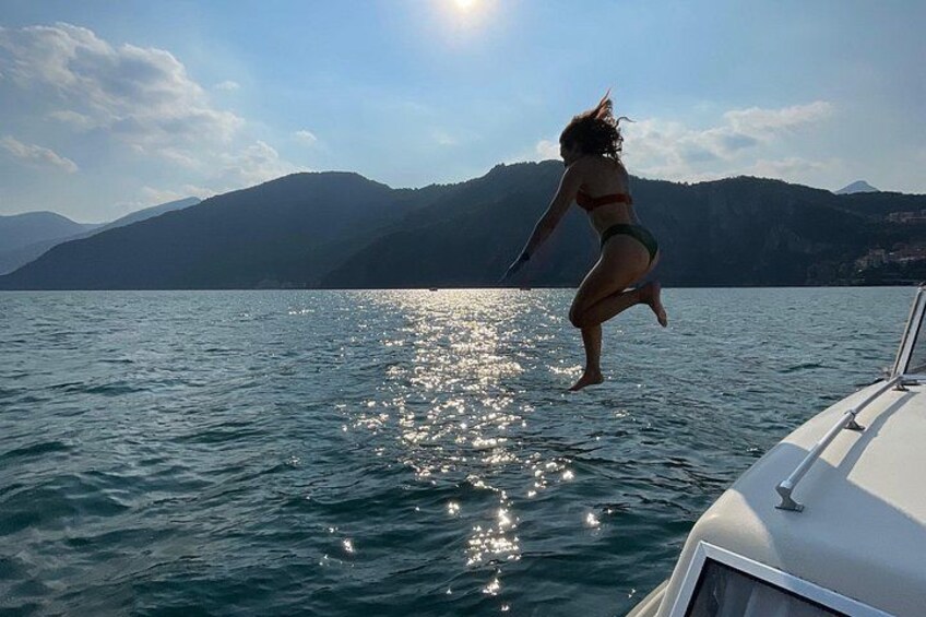 Una persona salta al agua desde un barco, con montañas al fondo. 5
