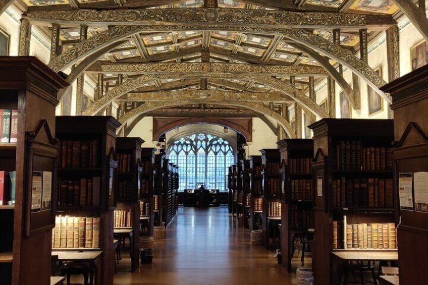 A library interior with ornate wooden bookshelves and a high, intricately designed ceiling. 4