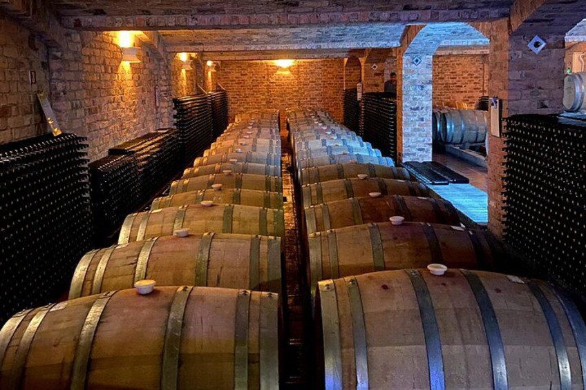 A wine cellar with wooden barrels and brick walls. 4