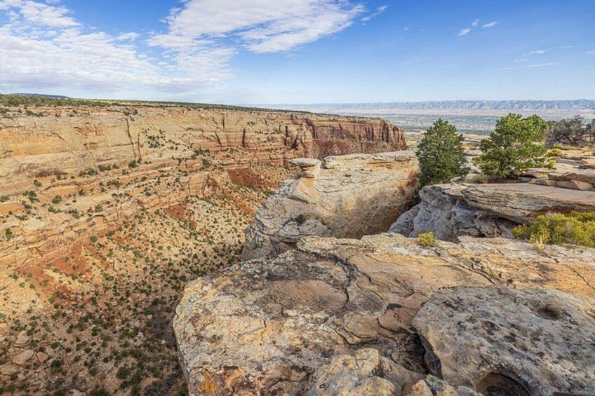Een ruig canyonlandschap met gelaagde rotsformaties en schaarse begroeiing. 5