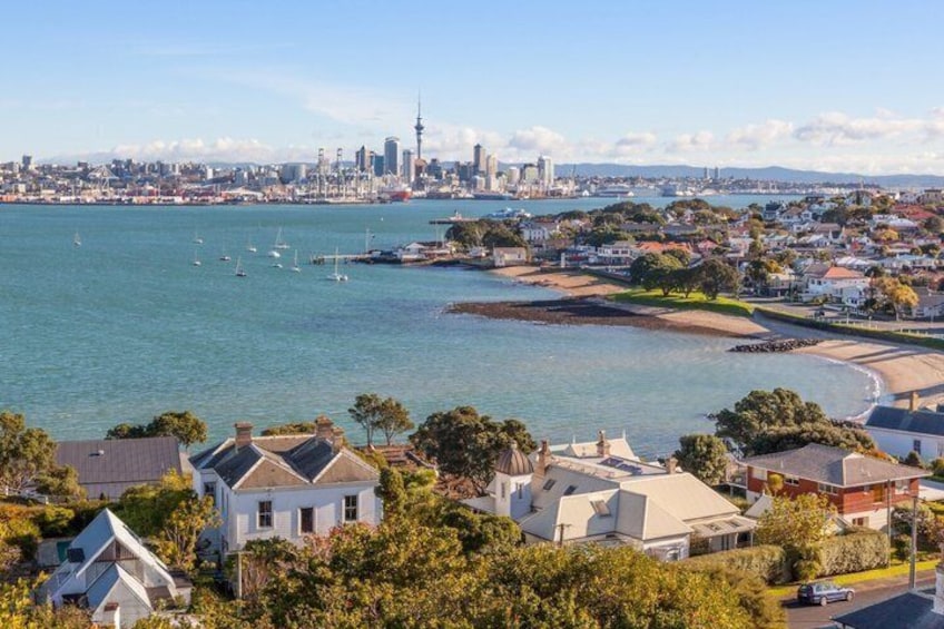 A coastal cityscape with residential houses, a marina, and a prominent tower in the distance. 3