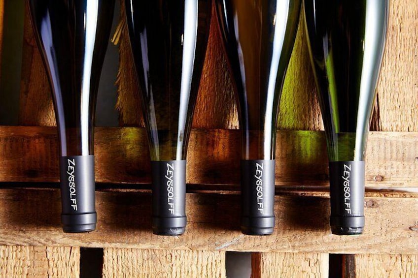 A row of wine bottles with labels ZEISSOLF on a wooden shelf. 2
