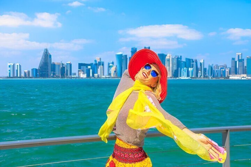 A person in a yellow and red outfit standing by a railing with a city skyline and water in the background. 1