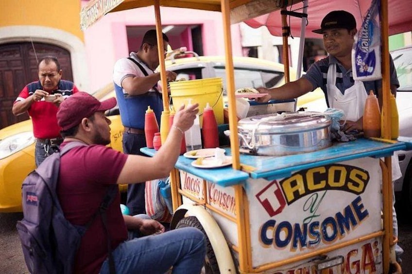 Un stand de restauration de rue portant l’inscription « Tacos a Consomé » où un homme prépare et sert des plats. 4