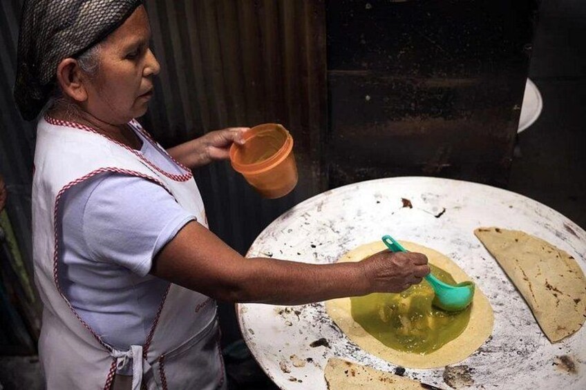 Une personne préparant des aliments, devant une grande surface de cuisson ronde, avec un bol contenant un liquide à proximité. 2