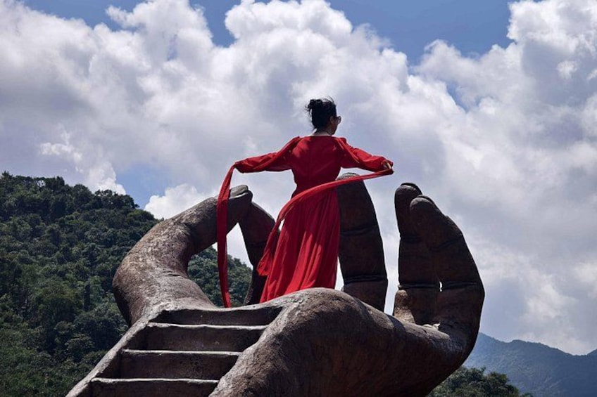 A person in a red dress standing on a rock formation with stairs. 3