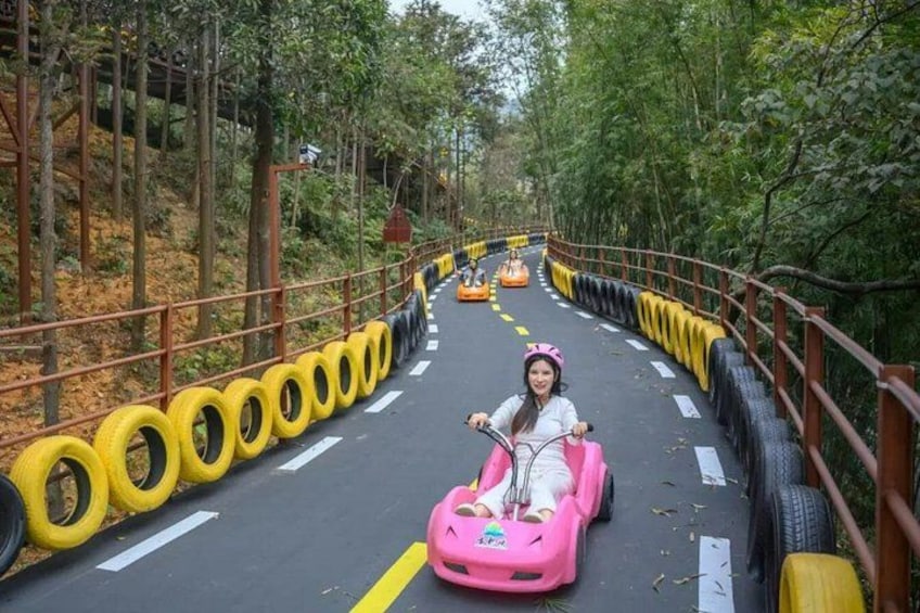 A person in a pink go-kart on a road lined with tires, surrounded by trees. 5
