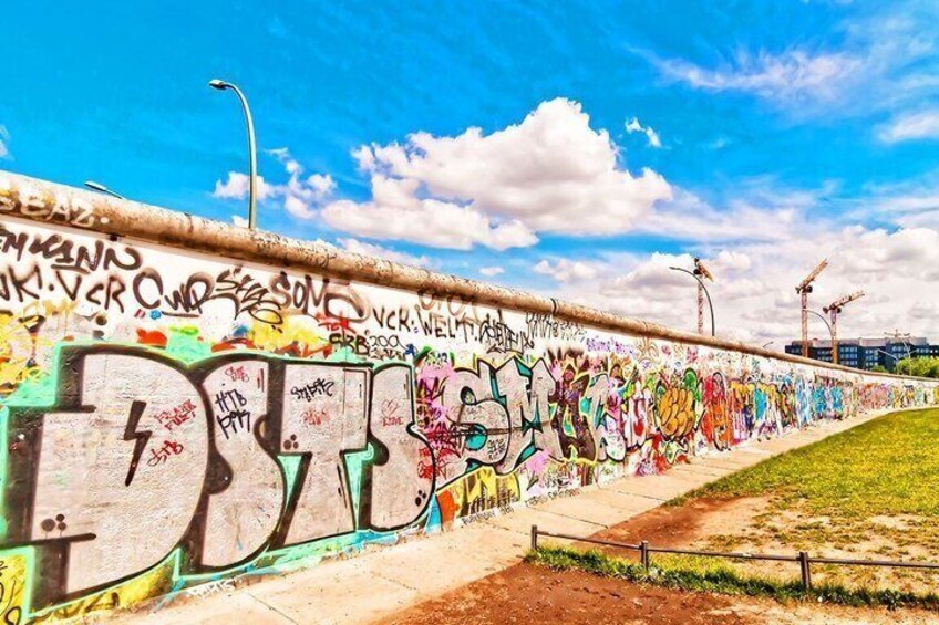 A graffiti-covered wall with large letters and colorful tags. 1