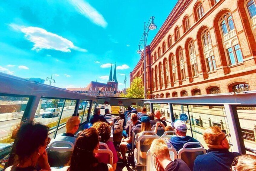 A bus with passengers looking out at a building with a spire. 5