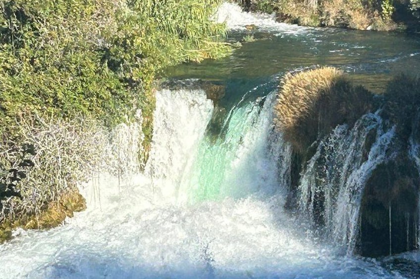 A waterfall with water cascading over rocks, surrounded by greenery. 2