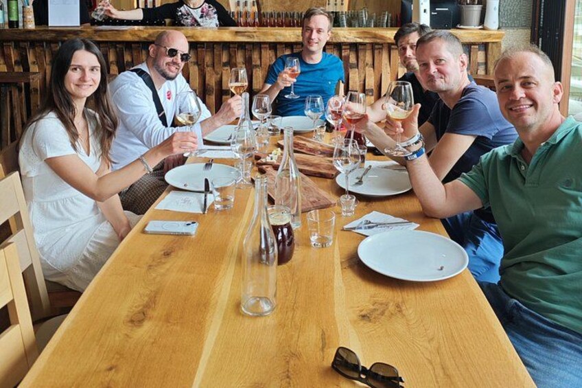 A group of people sitting at a wooden table in a restaurant, holding wine glasses. 1