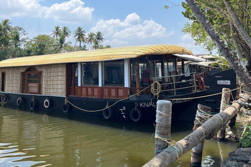 A houseboat docked at a pier with a yellow roof, surrounded by palm trees and calm water. 5