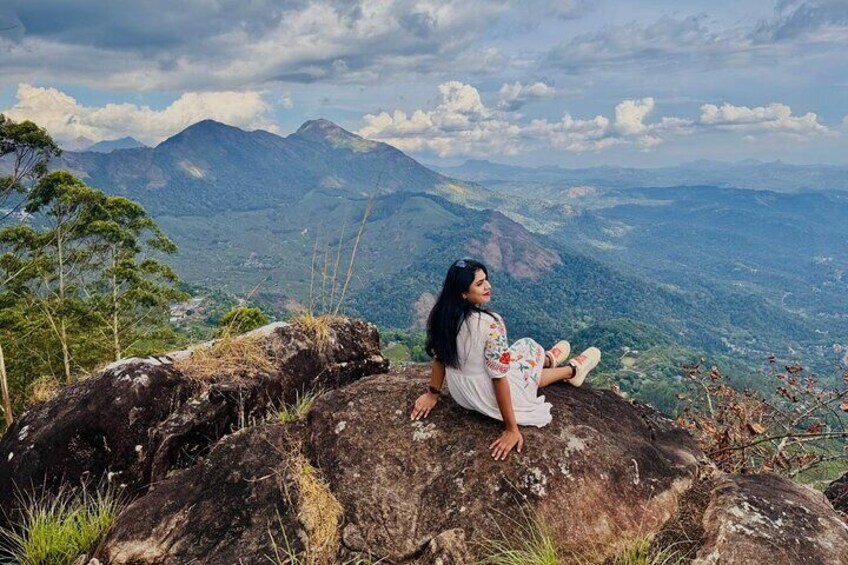 A person sitting on a rock with a mountainous landscape in the background. 3