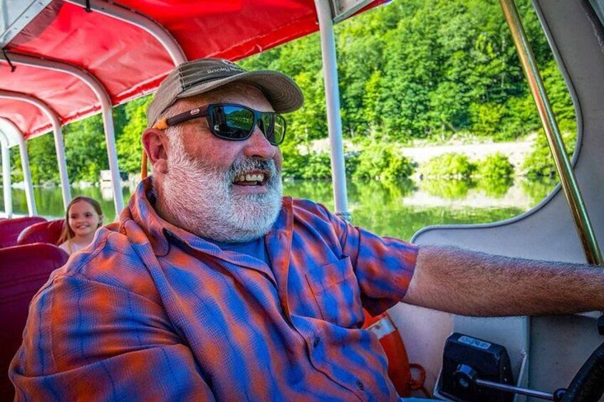 Ein Mann mit Karohemd fährt ein Boot mit rotem Verdeck. 3