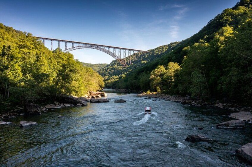 Ein Fluss mit einer Brücke, umgeben von üppigen grünen Hügeln. 2