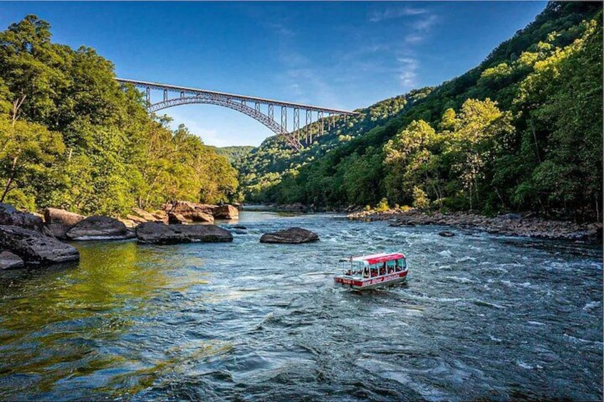 Ein Fluss mit einem Boot, einer Brücke und üppigen grünen Hügeln. 1