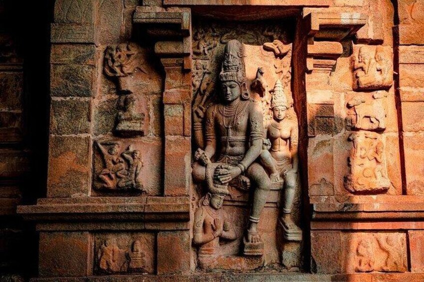 A stone carving of a seated figure with a headdress, flanked by smaller figures and intricate designs. 5