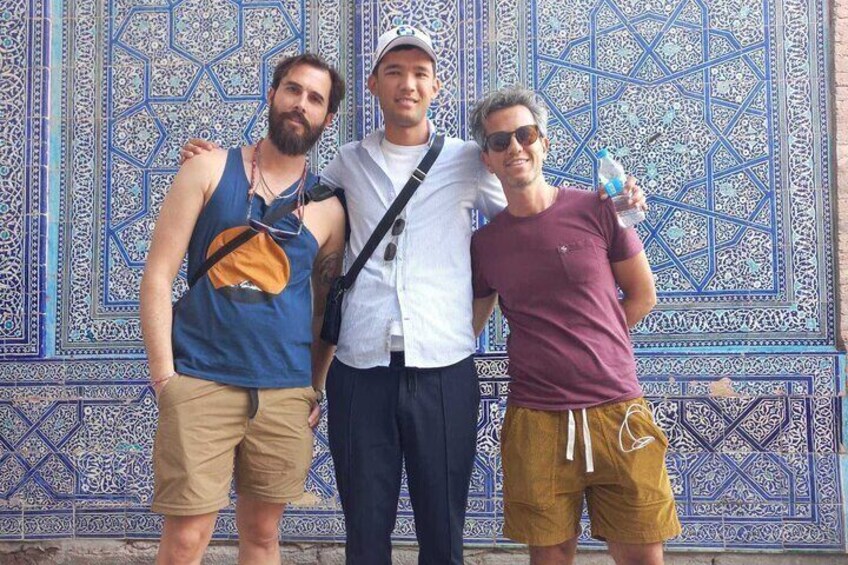 Tres personas de pie frente a una pared azul y blanca con diseño. 1