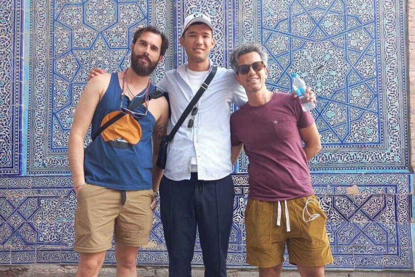 Three people standing in front of a blue and white patterned wall. 1