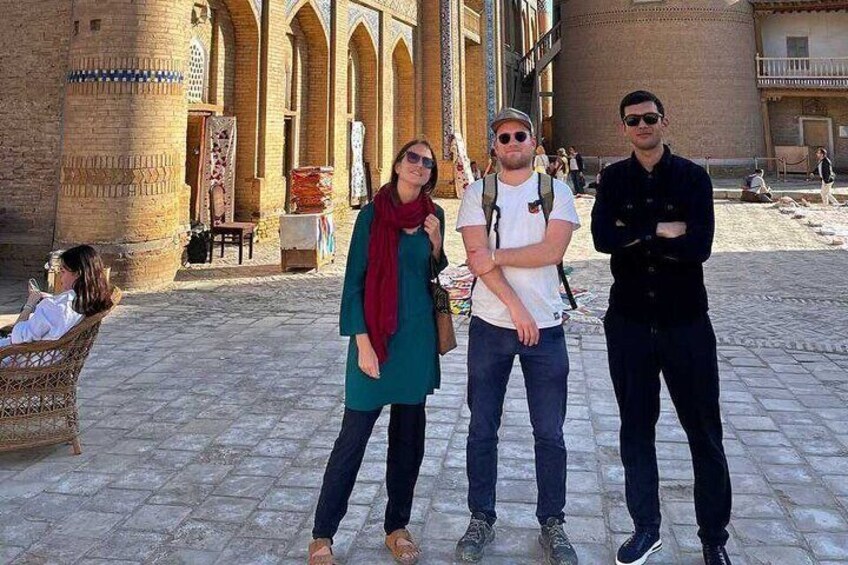 A group of people standing in front of a historic building with arches and a tiled courtyard. 5