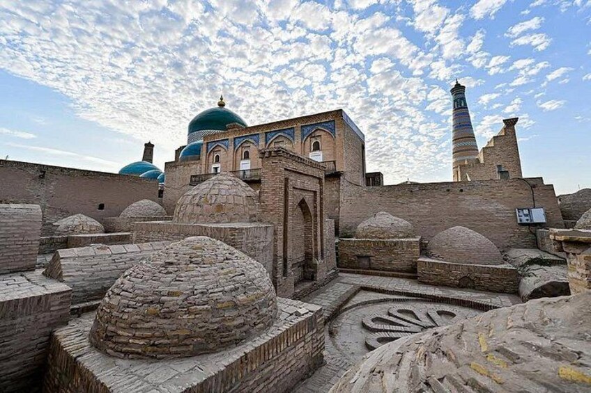 A historic courtyard with domed structures and a minaret. 3