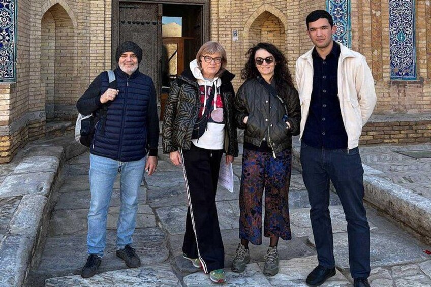 A group of people standing in front of a building with arched doorways and decorative tiles. 2
