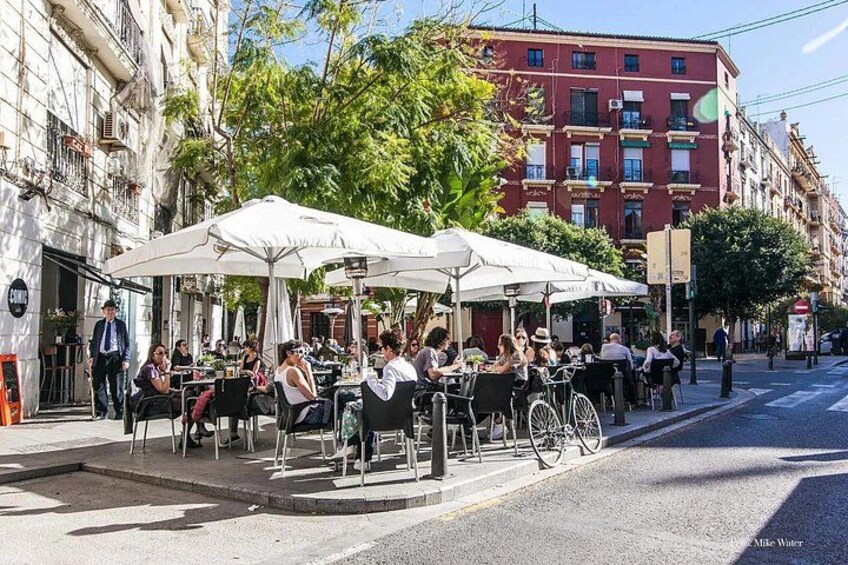 Mobiliario de café al aire libre con sombrillas, una calle y edificios. 1