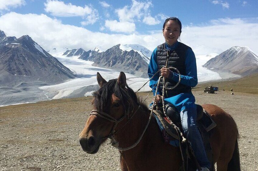 A person riding a horse on a mountain with a glacier in the background. 2
