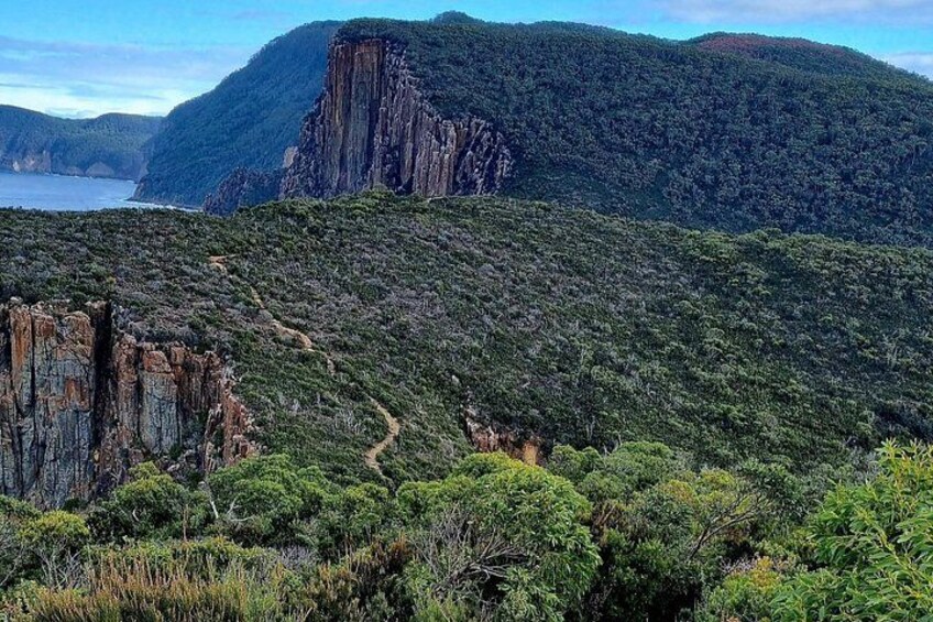 A rugged landscape with a prominent cliff and dense vegetation. 3
