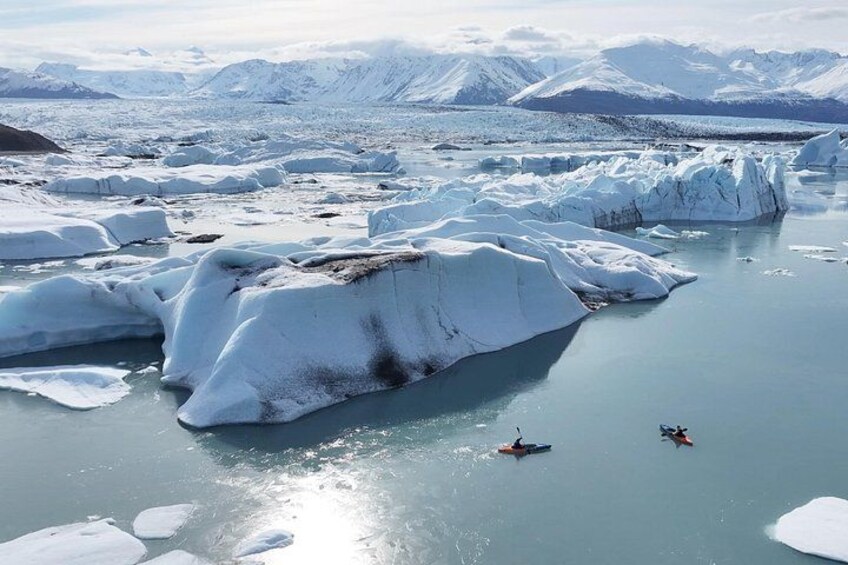 A glacier with icebergs and kayakers. 4