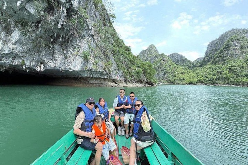 Eine Gruppe von Menschen auf einem grünen Boot in einem Fluss, umgeben von steilen Felsen. 3