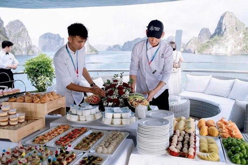 Zwei Köche bereiten Essen auf einem Boot zu, im Hintergrund ist ein malerischer Blick auf das Meer und die Berge zu sehen. 5