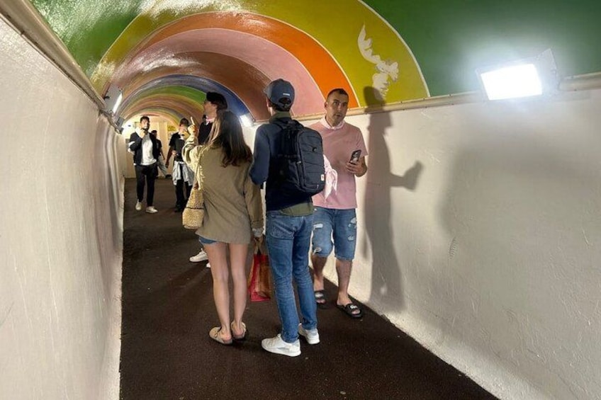 En tunnel med farverige buer, hvor en gruppe mennesker går igennem. 2