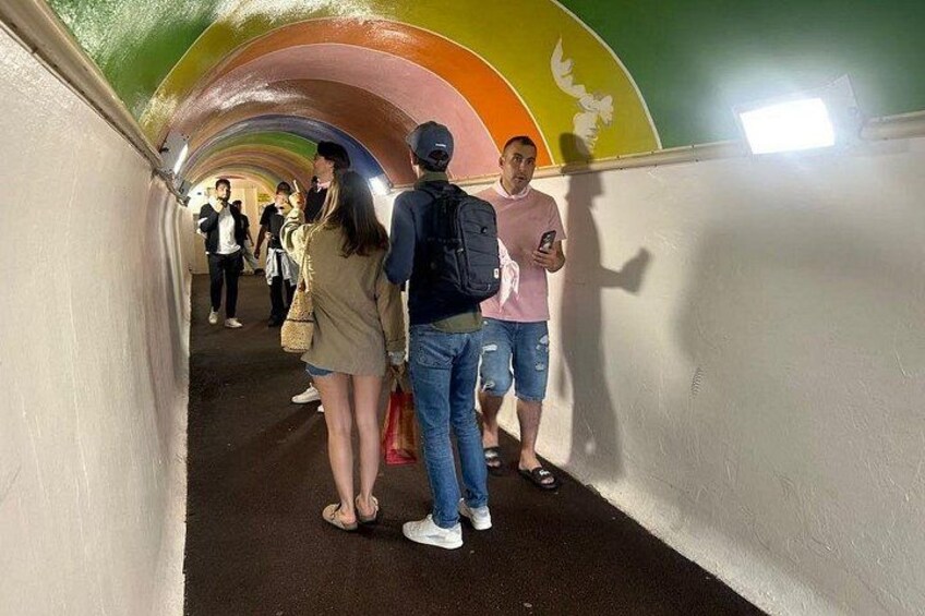 A tunnel with colorful arches and a group of people walking inside. 3