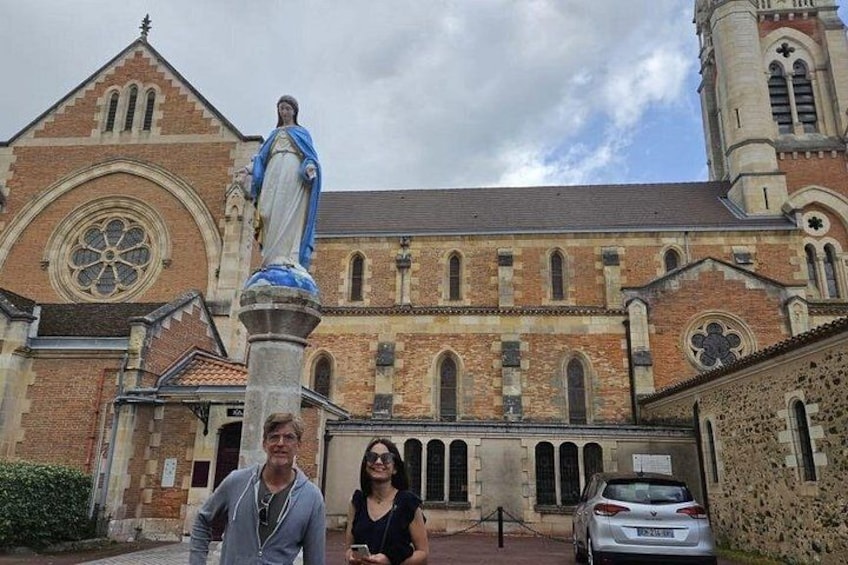 A church with a statue on a pedestal, a large rose window, and a bell tower. 4