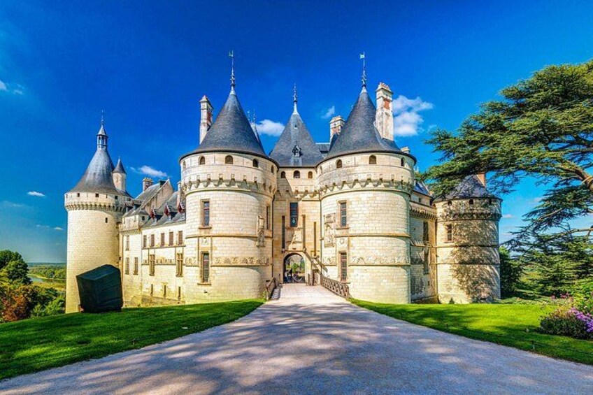 A castle with multiple towers, a paved pathway, and lush greenery. 5
