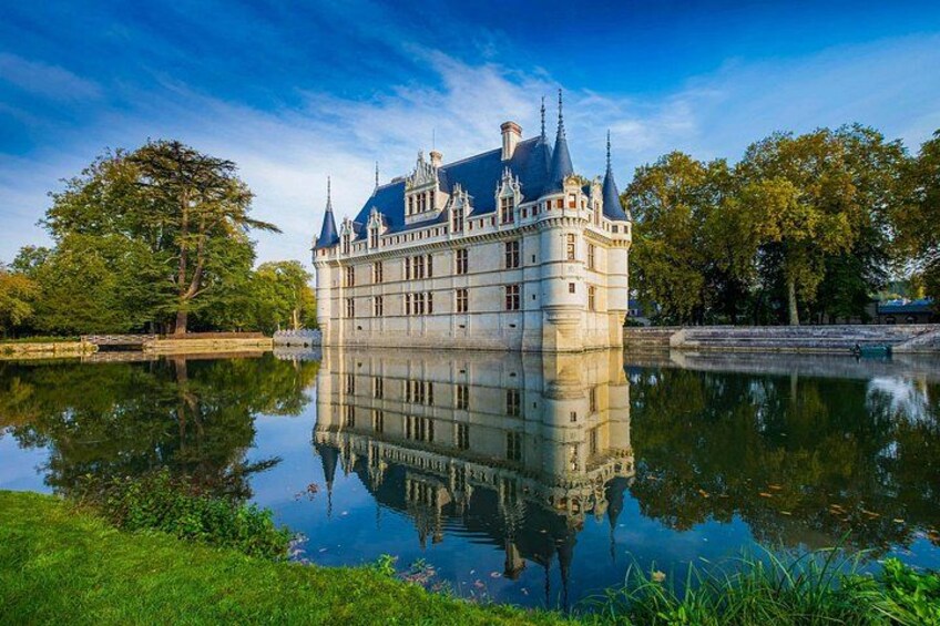 A castle with a moat, surrounded by trees and a clear sky. 4