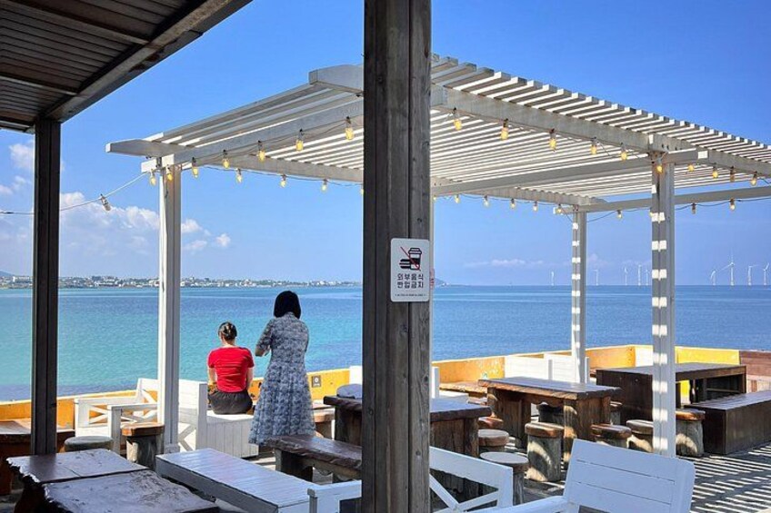 A covered outdoor seating area with tables and chairs overlooking a body of water. 3