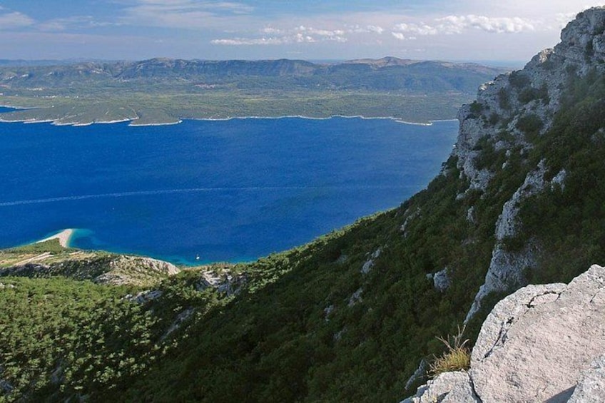 A coastal landscape with a clear view of the sea, a rocky cliff, and a distant shoreline. 5