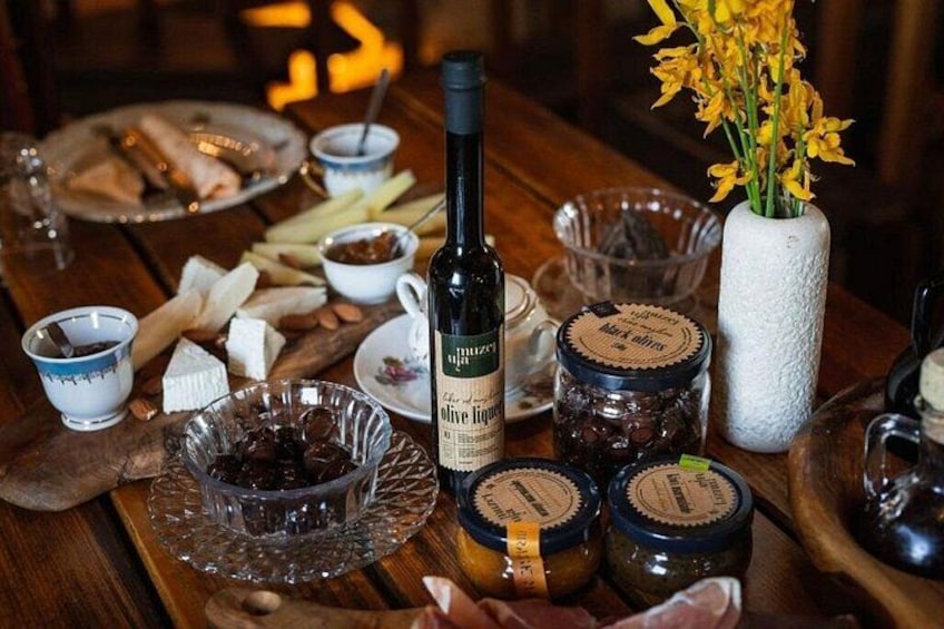 A wooden table with jars of olives, a bottle of olive oil, and a vase with yellow flowers. 2