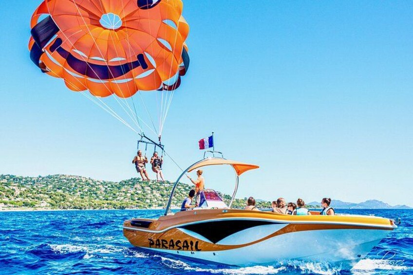 A parasailing boat with passengers and a parachute in the air. 2