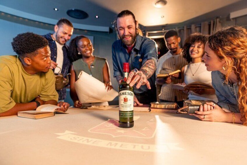 A group of people around a table with a bottle of Jamey Jayne Whiskey. 5