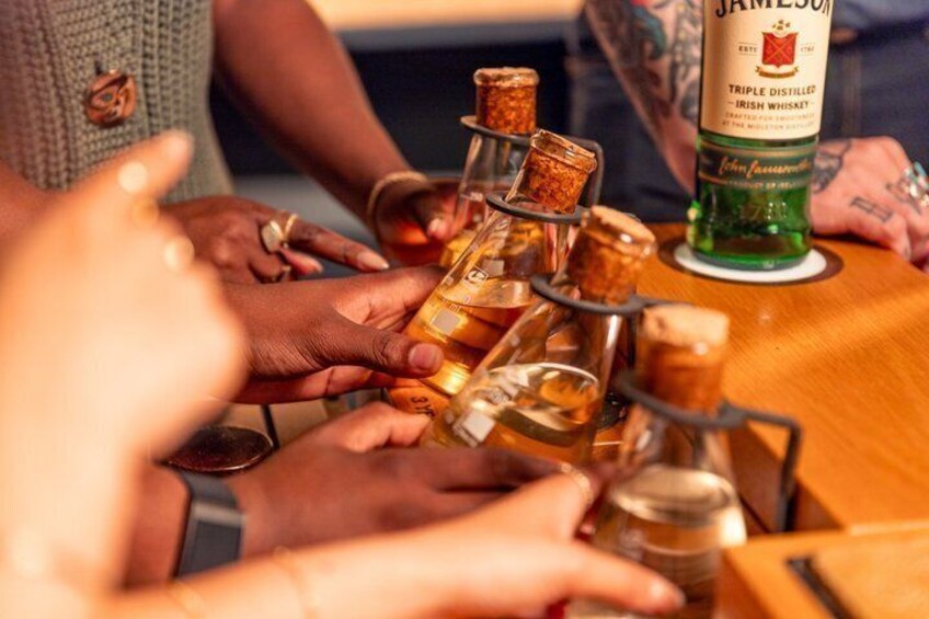 A group of people holding bottles of whiskey, with a bottle of Jameson Irish Whiskey visible. 3