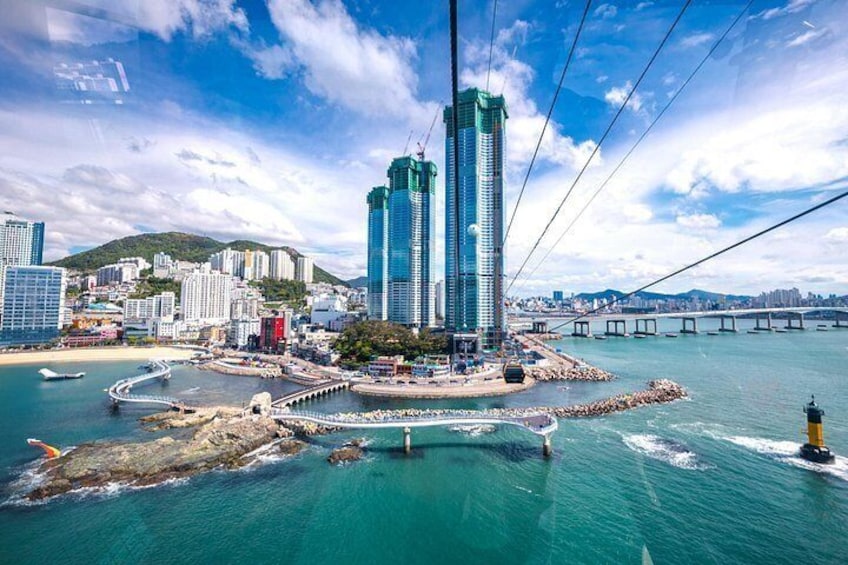 A coastal cityscape with a prominent skyscraper, a bridge, and a lighthouse. 1