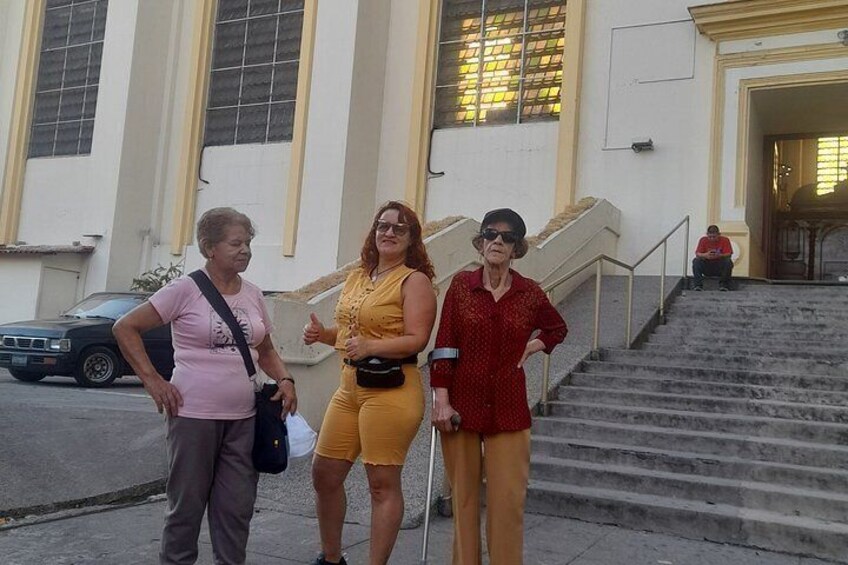 Three people standing in front of a building with large windows and a staircase. 1