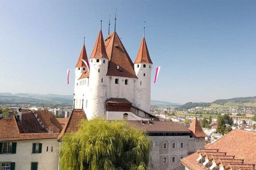 A castle with multiple towers, surrounded by buildings and a clear sky. 3