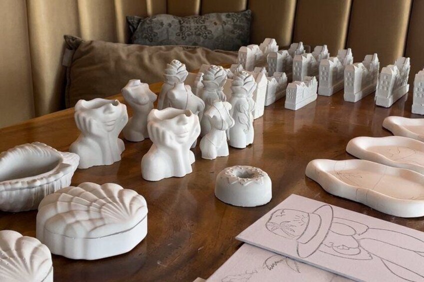A table with various white ceramic sculptures and a few sketches. 3